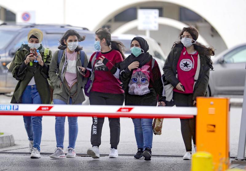 Young women wearing protective masks walk out of the Rafik Hariri University Hospital in the southern outskirts of Beirut, February 21. (AFP)