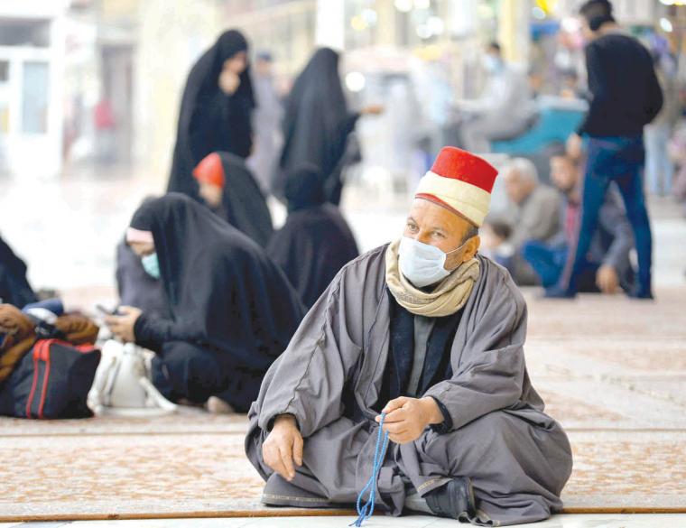 Worshippers wearing masks sit in the courtyard of the shrine of Imam Ali in the Iraqi central city of Najaf. (AFP)