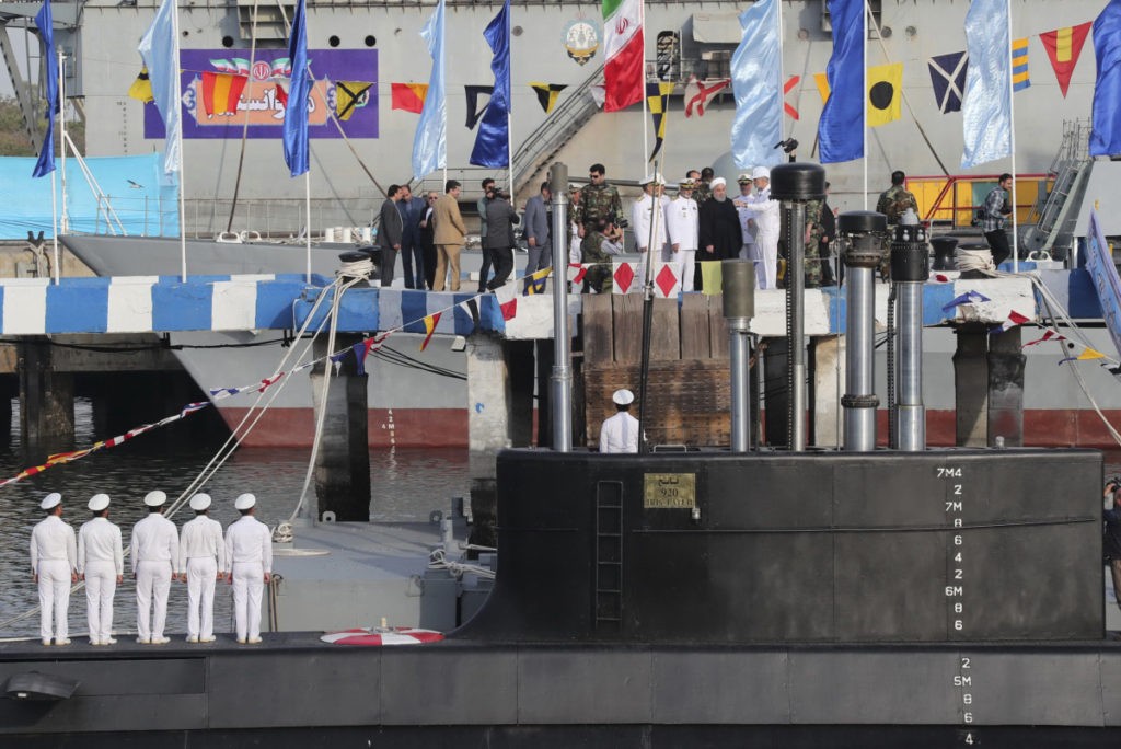 In this photo released by official website of the office of the Iranian Presidency, President Hassan Rouhani, center with white turban, and other dignitaries attend the inauguration of Fateh, "Conqueror" in Persian, Iranian made semi-heavy submarine in the southern port of Bandar Abbas, Iran, Sunday, Feb. 17, 2019. The Fateh has subsurface-to-surface missiles with a range of about 2,000 kilometers (1,250 miles), capable of reaching Israel and U.S. military bases in the region. (Iranian Presidency Office via AP)
