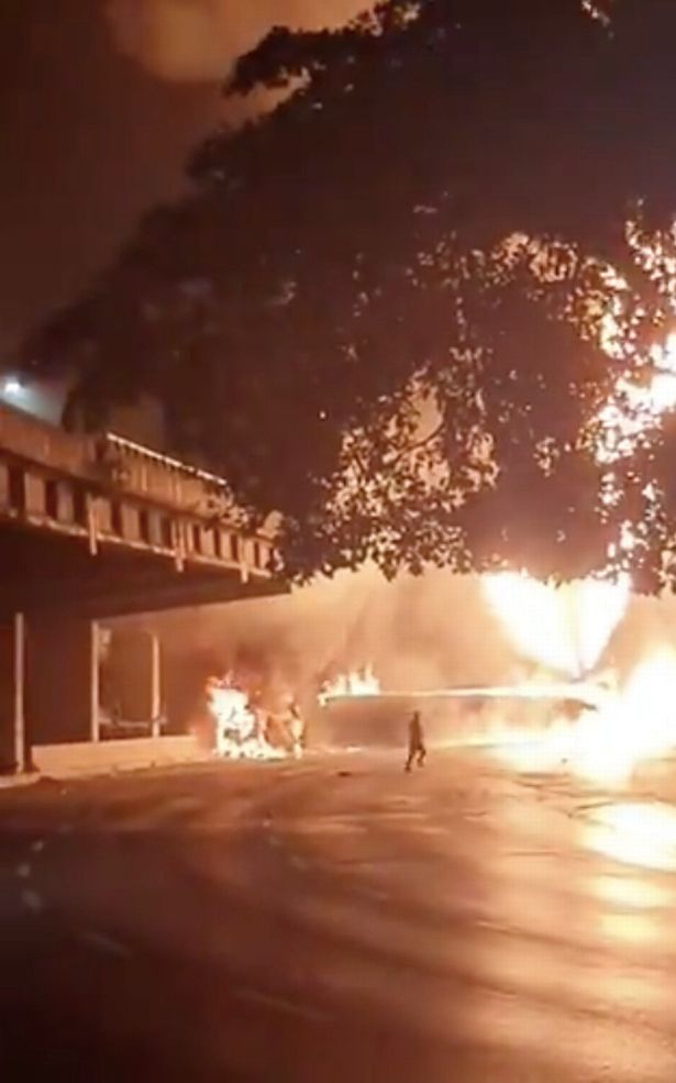 A figure runs in front of the huge flames