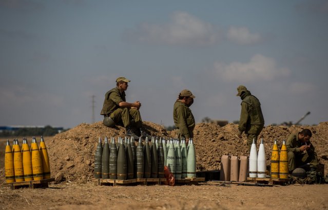 Israeli soldiers rest beside shells for a 155mm M109 Dores self-propelled howitzer at a position in Southern Israel near the border with Gaza, on the seventh day of Operation Protective Edge, on July 14, 2014.